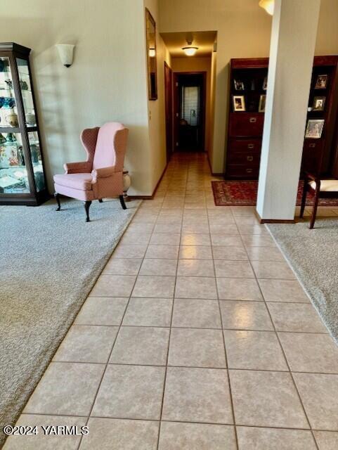 hallway featuring light tile patterned floors and light colored carpet