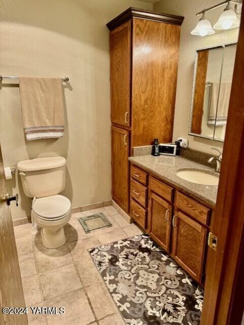 bathroom with toilet, vanity, and baseboards