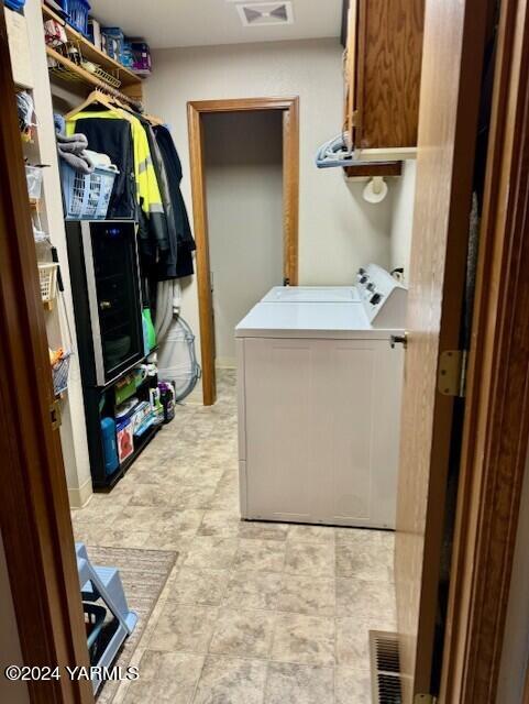 clothes washing area with washer and dryer, cabinet space, and visible vents