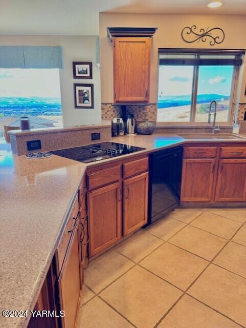 kitchen with light countertops, black appliances, brown cabinetry, and a sink