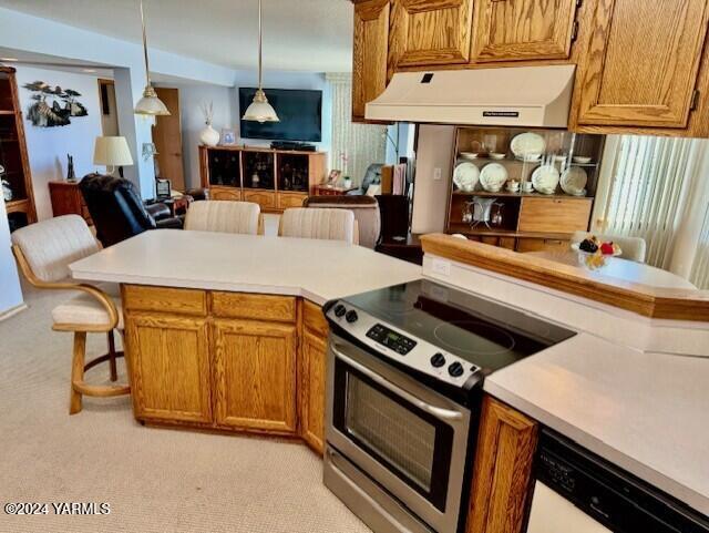 kitchen with stainless steel electric stove, light countertops, hanging light fixtures, a kitchen bar, and exhaust hood