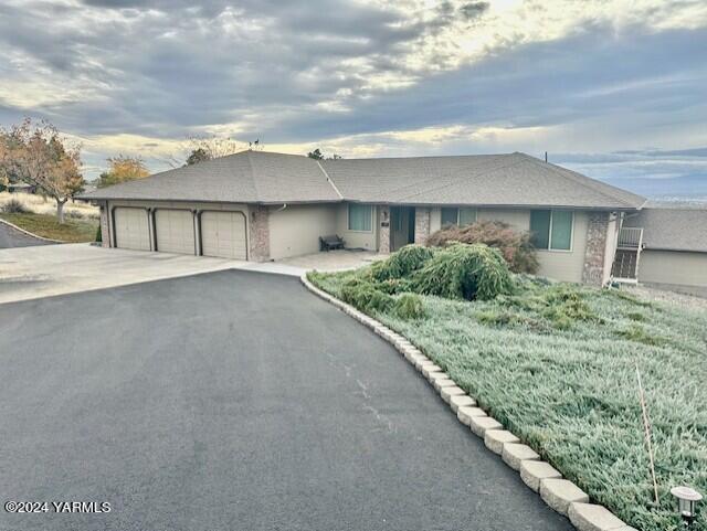 ranch-style home with a garage and aphalt driveway