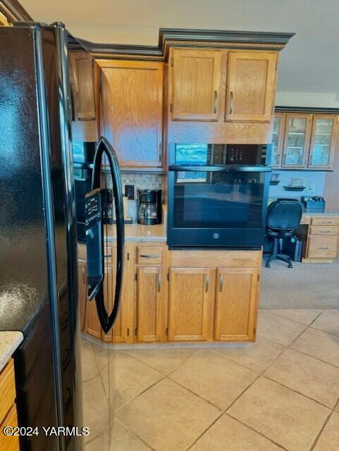 kitchen featuring black appliances, brown cabinetry, light countertops, and light tile patterned flooring