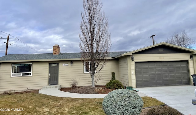 ranch-style house with roof with shingles, a chimney, concrete driveway, an attached garage, and a front lawn