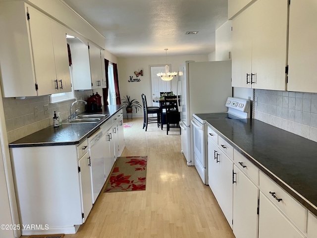 kitchen featuring dark countertops, white cabinets, a sink, light wood-type flooring, and white appliances