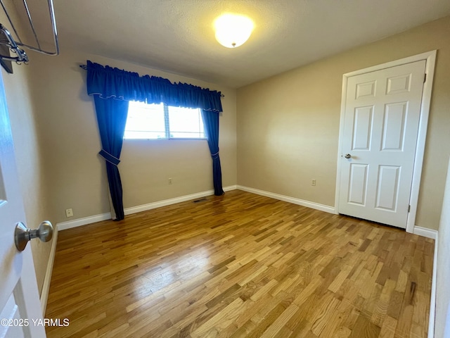 unfurnished bedroom featuring wood finished floors, visible vents, and baseboards