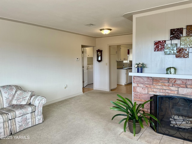 living room with light colored carpet, washer / clothes dryer, visible vents, and a fireplace