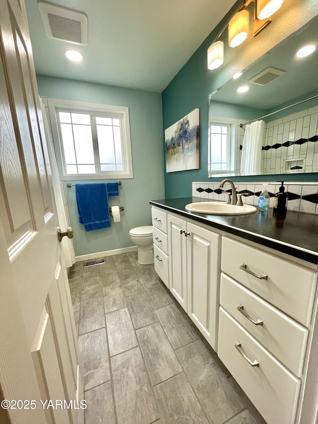 bathroom with toilet, baseboards, visible vents, and vanity