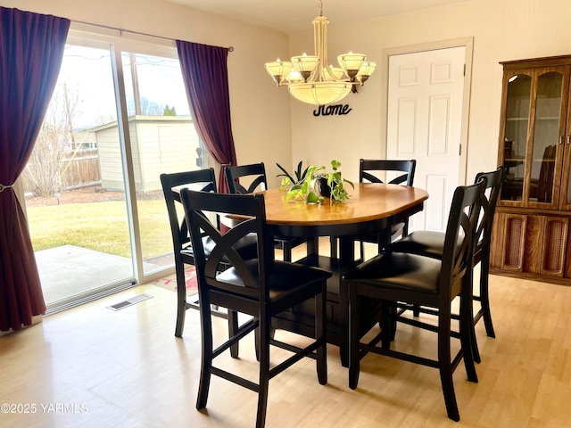 dining space with light wood-style floors, visible vents, and an inviting chandelier