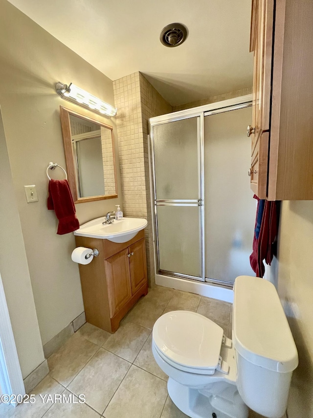 bathroom featuring toilet, a stall shower, tile patterned flooring, and vanity