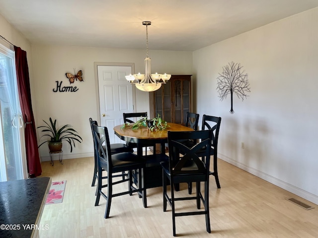 dining area with light wood-style floors, baseboards, visible vents, and a notable chandelier