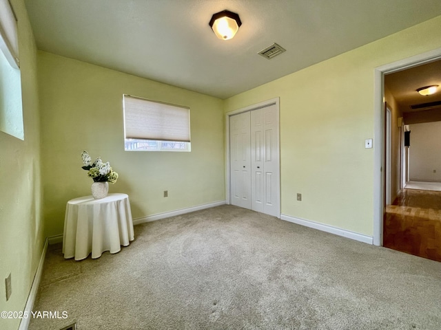 unfurnished bedroom with carpet floors, a closet, visible vents, and baseboards