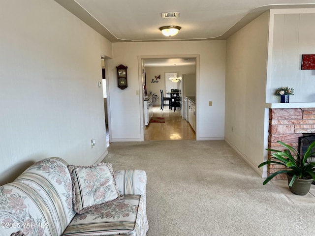 living area with baseboards, a fireplace, visible vents, and light colored carpet