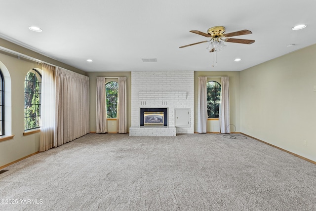 unfurnished living room with a brick fireplace, a ceiling fan, baseboards, and carpet flooring