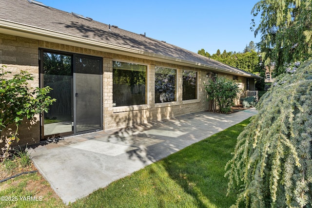 back of house featuring roof with shingles and a patio area