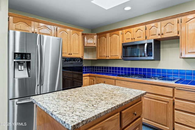 kitchen featuring a kitchen island, a skylight, tile counters, stainless steel appliances, and recessed lighting