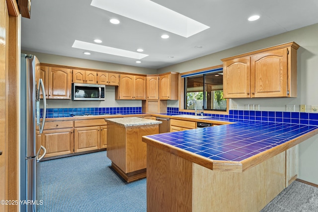kitchen featuring recessed lighting, a sink, carpet, appliances with stainless steel finishes, and a skylight