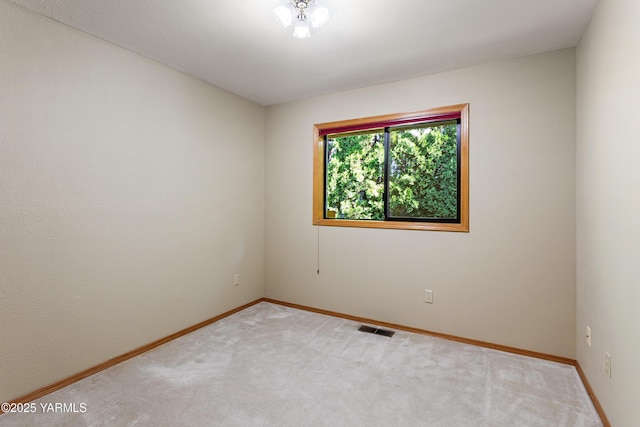 carpeted spare room featuring baseboards and visible vents