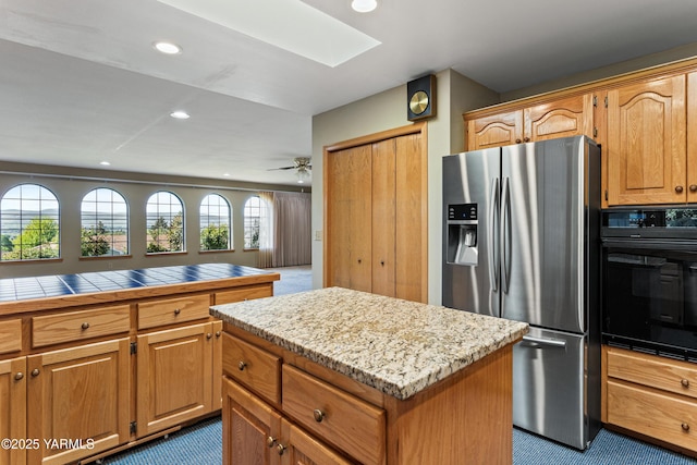 kitchen with carpet flooring, stainless steel fridge, black oven, recessed lighting, and a skylight