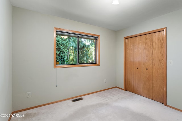 unfurnished bedroom featuring baseboards, visible vents, carpet, and a closet