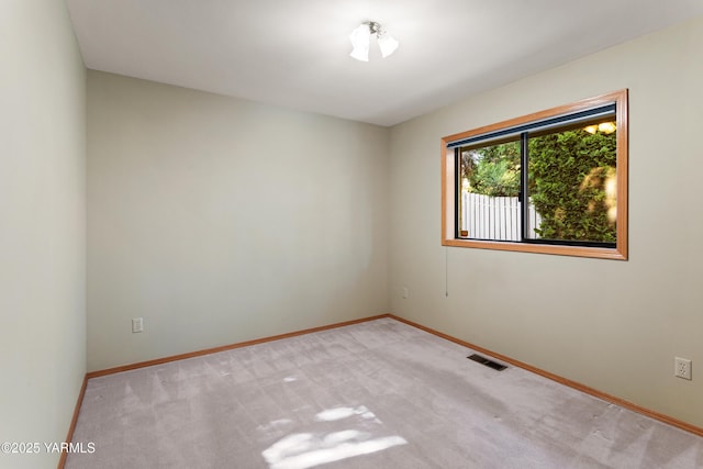 spare room featuring baseboards, visible vents, and carpet