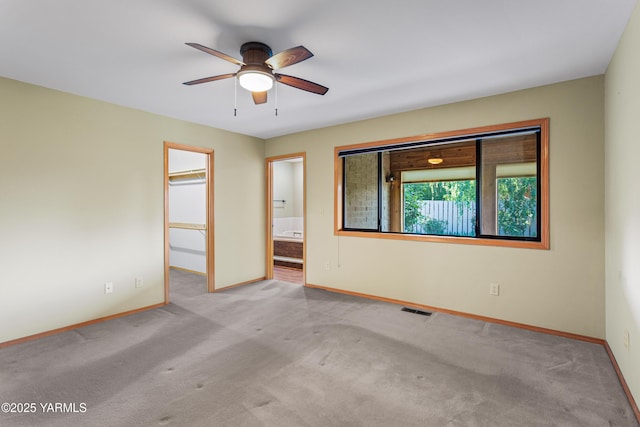carpeted spare room with visible vents, a ceiling fan, and baseboards