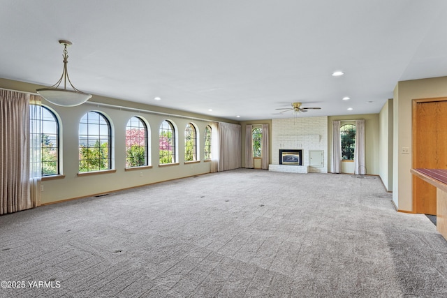 unfurnished living room with ceiling fan, light colored carpet, a brick fireplace, baseboards, and recessed lighting