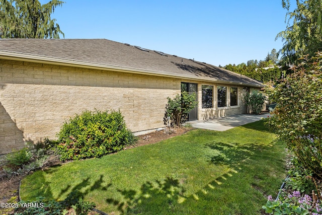 back of property featuring a yard, a patio, and a shingled roof