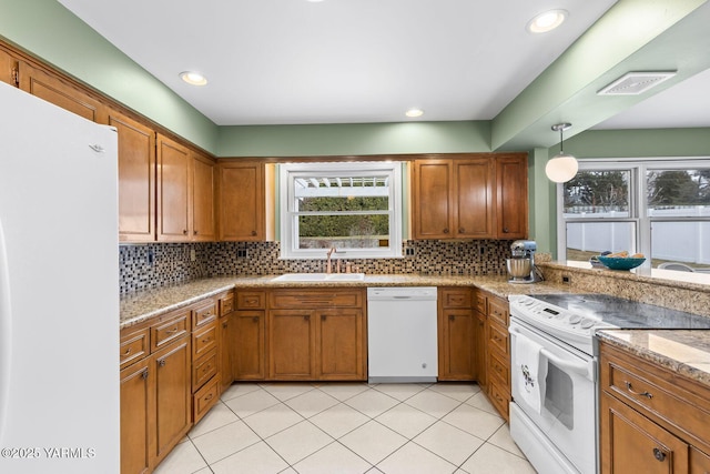 kitchen featuring brown cabinetry, a sink, and white appliances