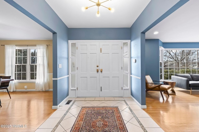 entryway featuring baseboards, a notable chandelier, and visible vents