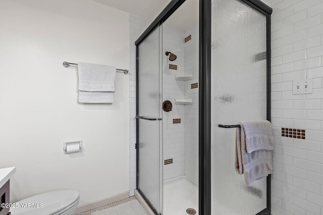 bathroom with a shower stall, baseboards, vanity, and toilet