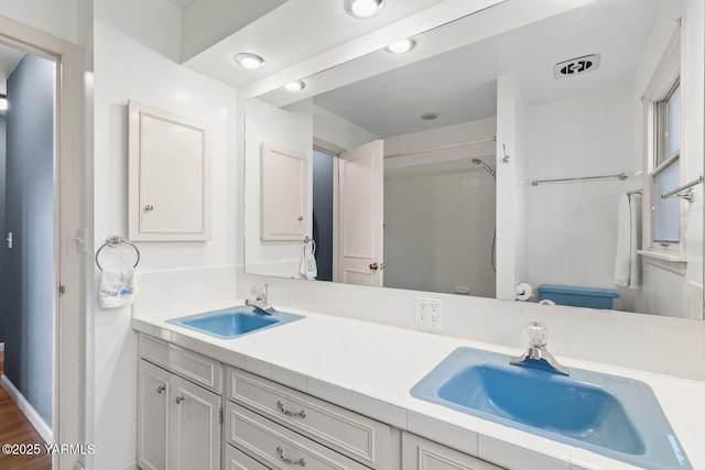 full bathroom featuring walk in shower, double vanity, and a sink