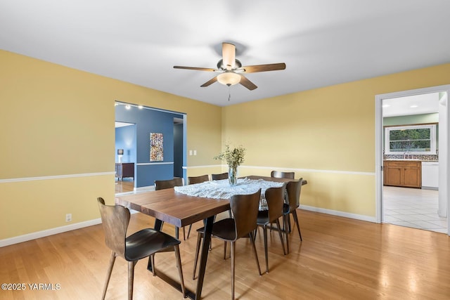 dining area featuring baseboards, light wood-style flooring, and a ceiling fan