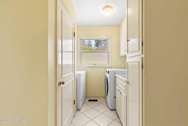 clothes washing area featuring light tile patterned floors, baseboards, washing machine and dryer, and cabinet space