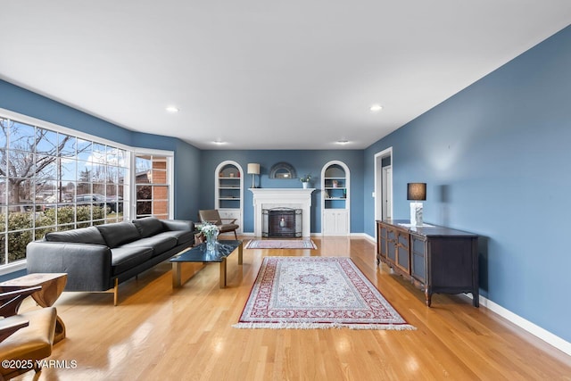 living room with a fireplace, wood finished floors, baseboards, and built in features