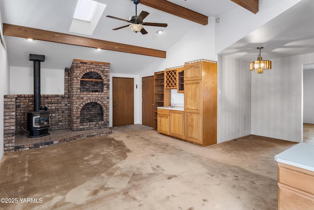 6520 Barge St, Yakima, WA 98908 - unfurnished living room with light colored carpet, beam ceiling, a skylight, a wood stove, and ceiling fan with notable chandelier