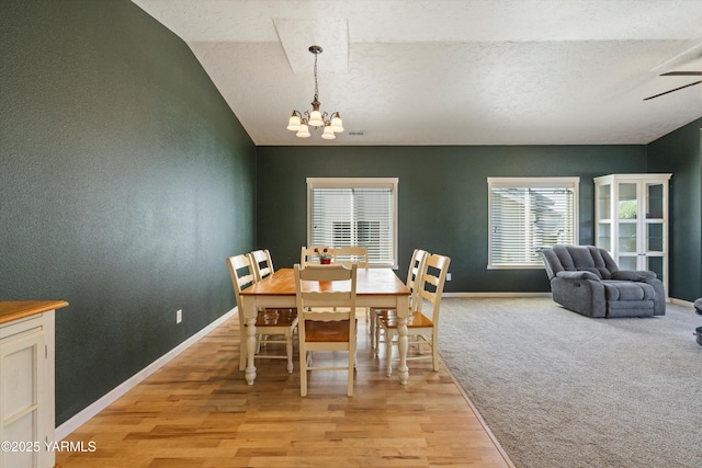 dining room featuring light wood-style floors, a textured ceiling, baseboards, and a notable chandelier