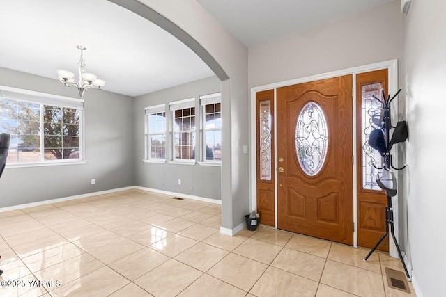 entryway with arched walkways, light tile patterned floors, visible vents, a chandelier, and baseboards