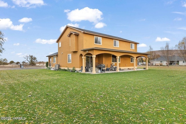 rear view of property featuring central AC, a yard, a patio, and stucco siding