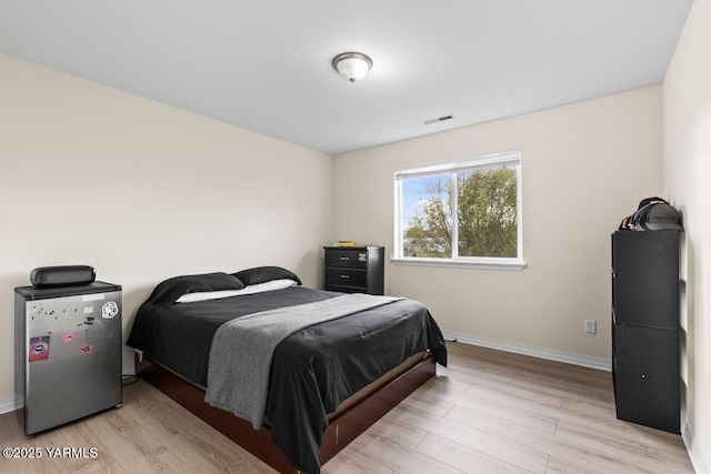 bedroom with light wood-type flooring, visible vents, and baseboards