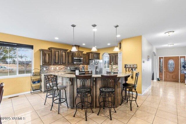 kitchen with tasteful backsplash, visible vents, arched walkways, stainless steel appliances, and light tile patterned flooring