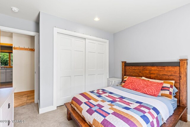 bedroom featuring light carpet, a closet, and baseboards