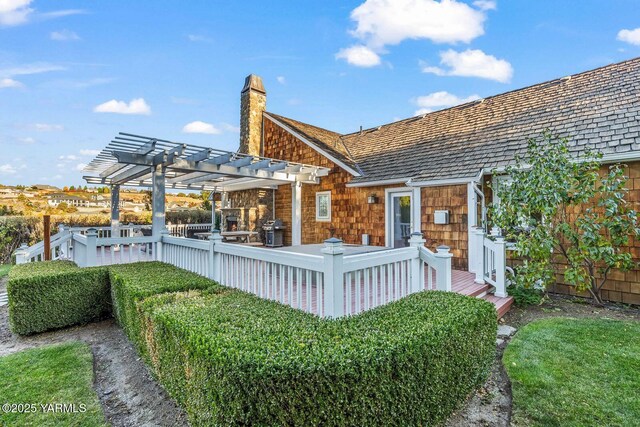back of house with a deck, a pergola, and a chimney