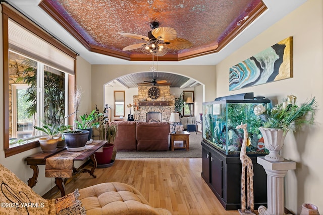 12900 Douglas Rd, Yakima, WA 98908 - living room with a raised ceiling, a stone fireplace, ceiling fan, light wood finished floors, and arched walkways