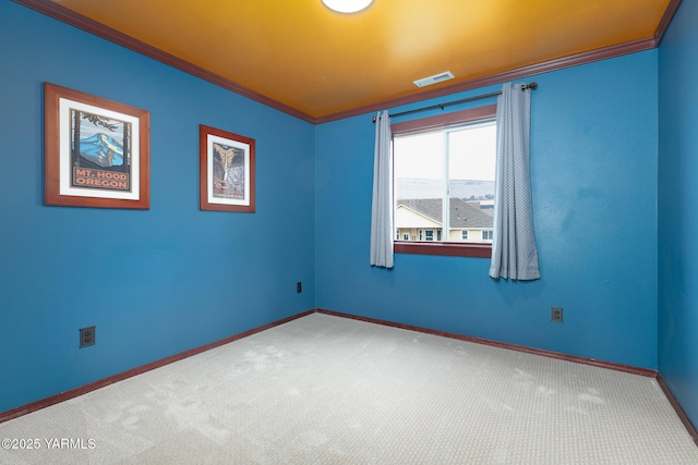 carpeted empty room with baseboards, visible vents, and crown molding