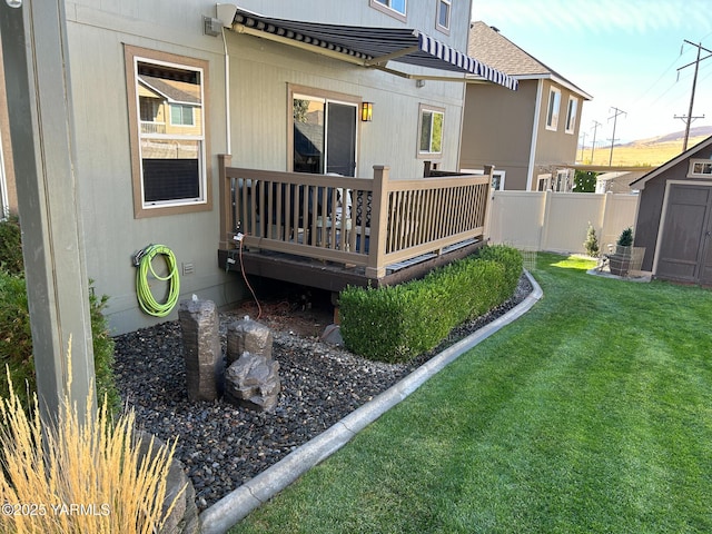 back of house featuring an outbuilding, a lawn, a storage shed, fence, and a wooden deck