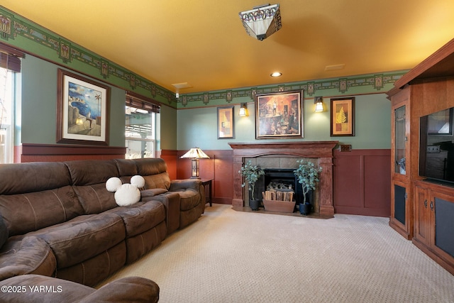 living room with light carpet, wainscoting, a tile fireplace, and plenty of natural light