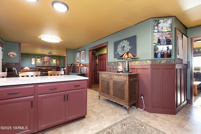 kitchen featuring open floor plan, light countertops, and a wainscoted wall