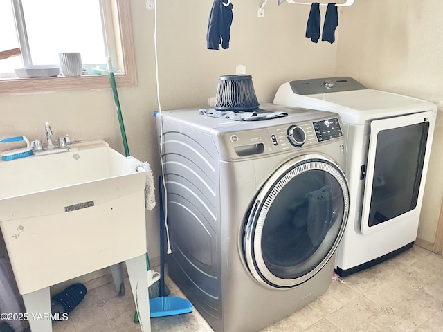 clothes washing area featuring laundry area, washer and dryer, and a sink