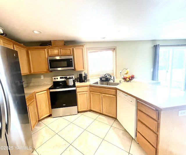 kitchen featuring light countertops, light tile patterned floors, a peninsula, stainless steel appliances, and a sink